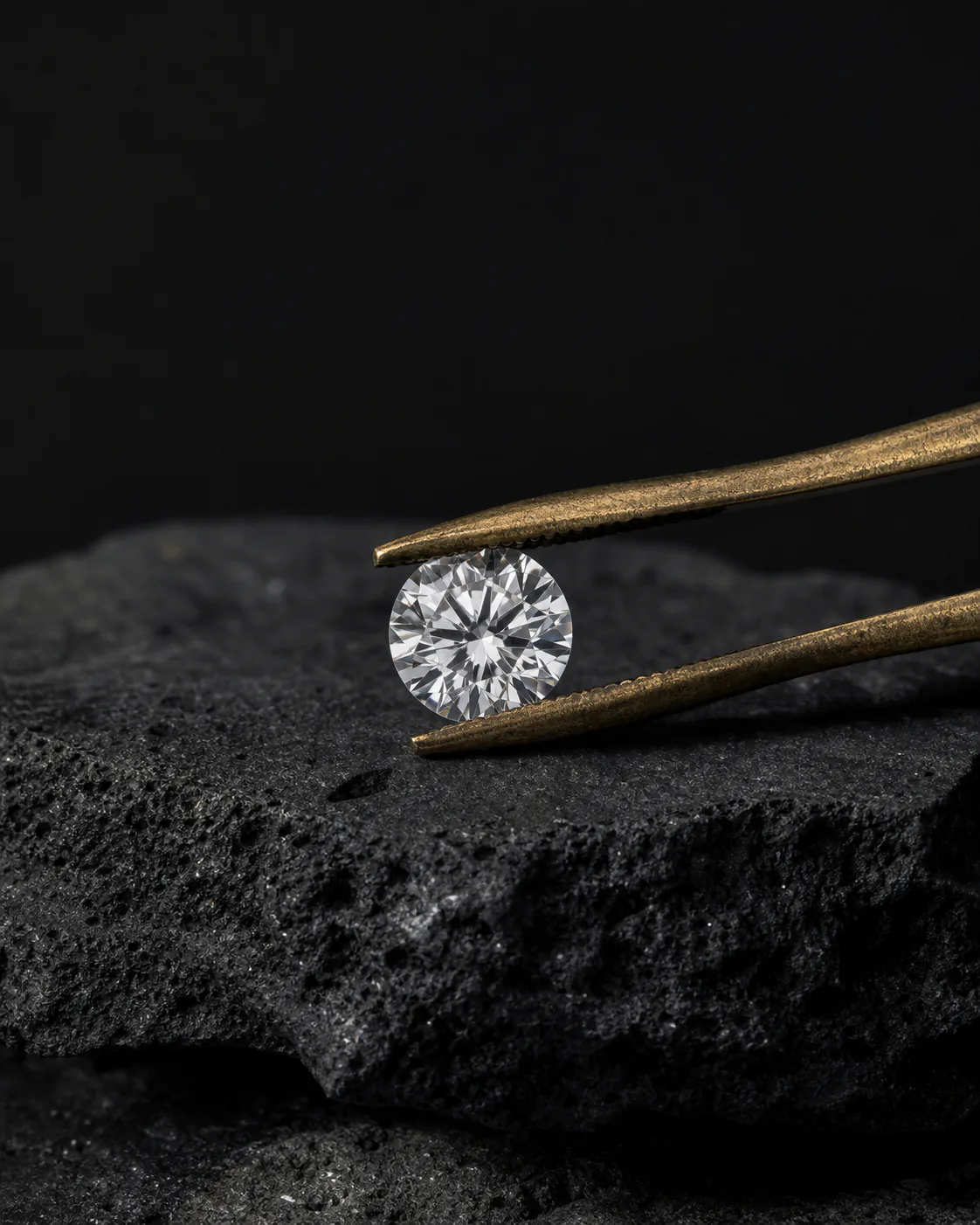 Round brilliant lab-grown diamond held in antique brass tweezers