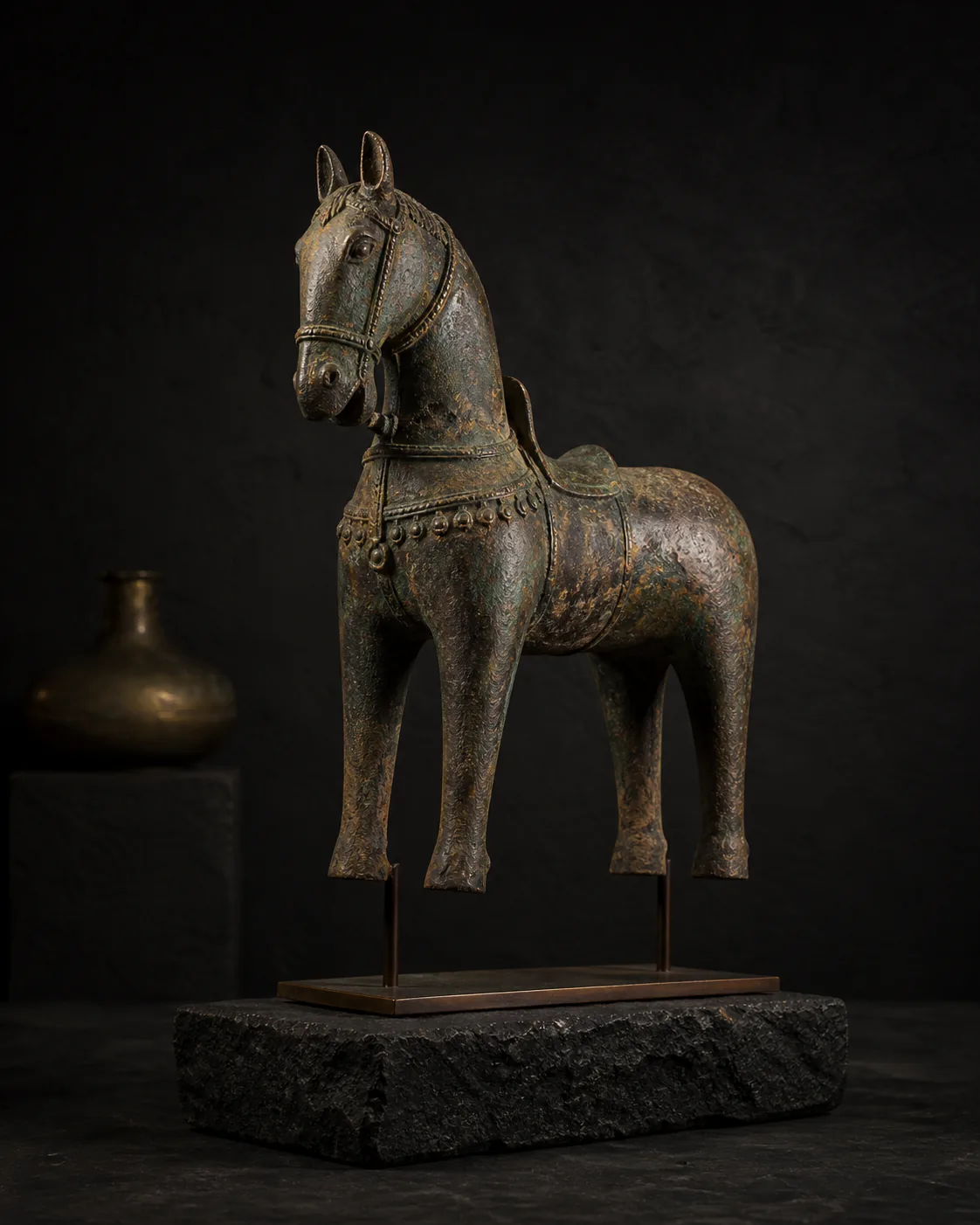 Weathered bronze horse sculpture displayed on dark stone